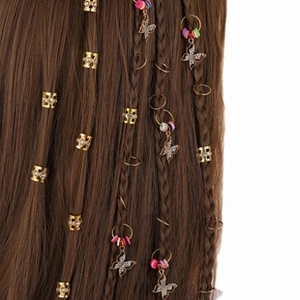 Detail of golden dreadlock cuffs with rhinestones and colorful butterfly charms on braids