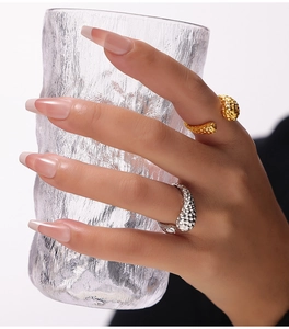 Detail view of irregular hammered gold and silver rings worn with glass accessory