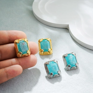 Close-up of vintage 18K gold and silver earrings with rectangle blue-green stones