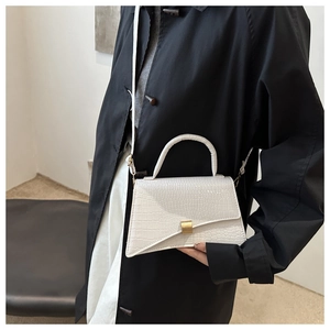 Detail view of white crocodile pattern shoulder bag with a stylish gold metal clasp