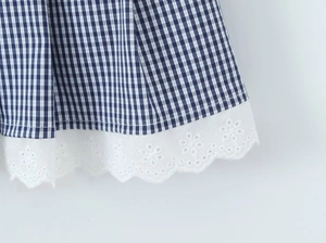 Detail of blue and white gingham fabric hem with intricate white lace embroidery