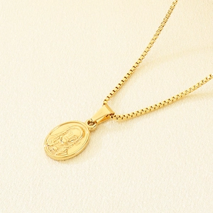 Vue macro d'un pendentif ovale doré avec relief de Jésus sur une chaîne carrée