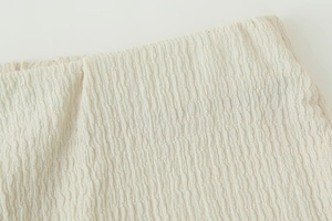 Detailed macro view of cream pleated fabric with textured elastic waist structure