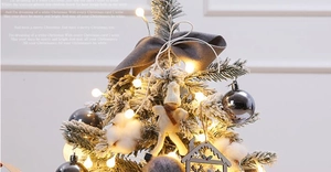 Close-up of flocked mini Christmas tree with warm LED lights and grey velvet bow