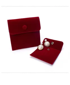 Red velvet jewelry pouch with snap button closure and retro pearl earrings on white background