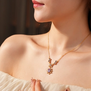 Macro shot of vintage gold necklace with oval purple gemstone and zircon floral accents