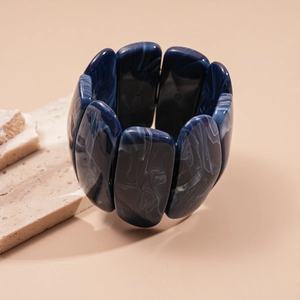 Detail of blue marble acrylic stretch bracelet blocks on light textured stone