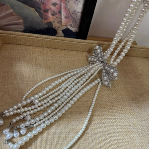 Elegant multi-layer pearl necklace with silver bow pendant and sparkling rhinestones