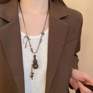 Detail of vintage wooden gourd pendant necklace with star charm on leather cord