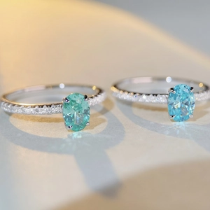 Macro shot of S925 silver rings with emerald and aquamarine stones and pavé diamonds