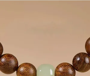 Macro detail of natural golden Phoebe wood beads with a smooth green jadeite accent stone