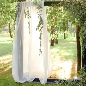 Close-up of white chiffon fabric draped over a wooden frame with green eucalyptus leaves