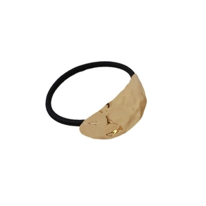 Minimalist gold textured metal pendant with black elastic hair tie on a white background
