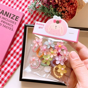 Close-up of flower hair ties in pastel colors and clear packaging on a cozy background