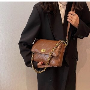 Detail of brown quilted leather bag with gold chain and metal twist lock on model