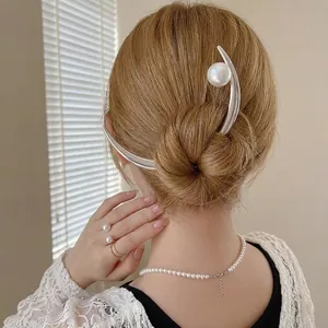 Elegant curved silver hair pin with pearl accent styled in a modern bun hairstyle