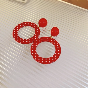 Detail of red and white polka dot hoop earrings on a textured background