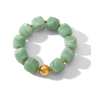 Detailed macro view of green marble-textured cube beads and gold spacers on a chic bracelet