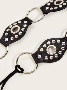 Macro view of punk style black leather belt with silver metal rings and hollow rivets