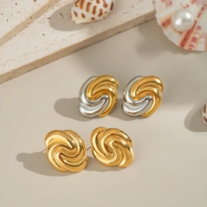 Textured 18K gold and silver twist knot earrings displayed on elegant stone and shell decor