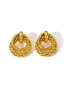 Detailed close-up of gold door knocker earrings featuring a textured beaded ring design