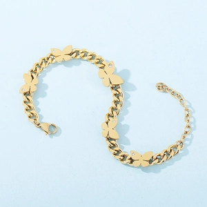 Macro shot of gold butterfly charm bracelet with tiny diamonds on a light blue surface
