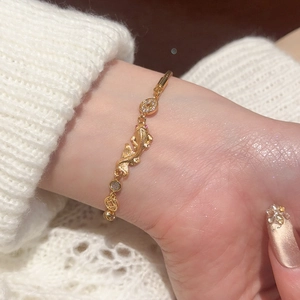Detail of gold koi fish bracelet with red zircon eyes and decorative hollow coin elements