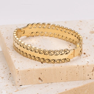Vintage gold leaf pattern stainless steel bangle with clasp on stone surface