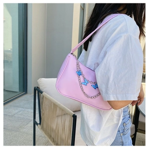 Close-up of pink shoulder bag with silver chain featuring blue butterfly pendants