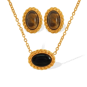 Vintage gold necklace set with oval tiger eye stones and black gems on white background