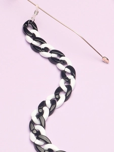 Close-up of minimalist black and white acrylic resin chain for eyewear on purple base