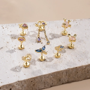 Golden heart, butterfly and cloud stud earrings with zircon on beige stone display