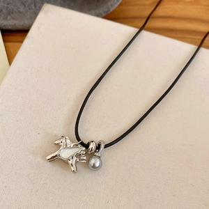 Gros plan détaillé du pendentif cheval en zircon et perle grise sur collier en corde