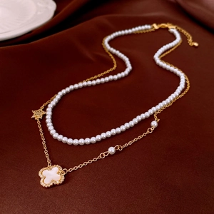 Detailed close-up of double-layer pearl and gold flower pendant necklace on silk background