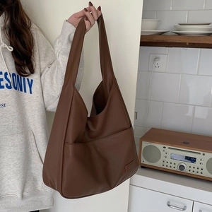 Nahaufnahme der braunen Leder-Tragetasche mit praktischer Fronttasche getragen von Model zu Hause