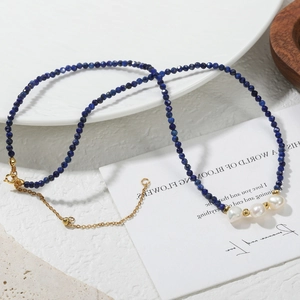 Macro detail of blue lapis beads and white pearls on a gold adjustable necklace