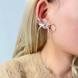 Close-up of silver bow stud earring with long snake chain tassels on a female model