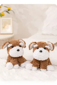 Close-up of two plush Schnauzer dogs with realistic curly fur and white beard on a bed