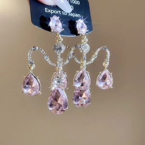 Détail macro de boucles d'oreilles pendantes en cristal rose et finitions dorées