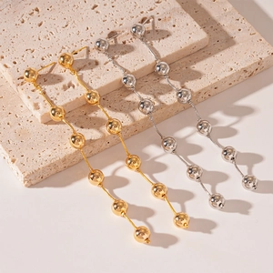 Elegant gold and silver beaded tassel drop earrings displayed on natural stone platforms