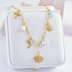Detail of gold ocean-themed necklace featuring cross, pearl, and dolphin pendants