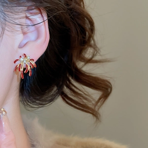 Gros plan sur des boucles d'oreilles feu d'artifice en émail rouge et cristaux dorés
