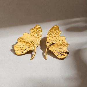 Detailed macro shot of golden hammered gingko leaf earrings with textured metal finish