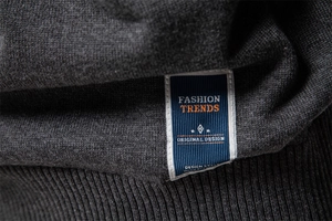 Macro view of dark grey knit sweater texture featuring a fashion trend side label