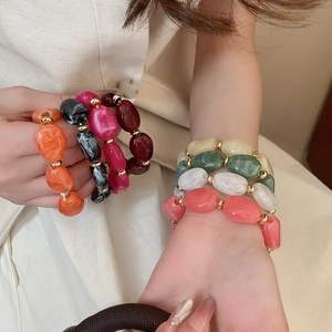 Close-up of irregular acrylic bead bracelet with marble texture and golden spacers