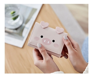 Close-up of pink pig-shaped tri-fold wallet with heart-shaped ears held by hands