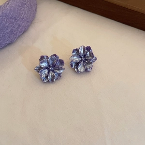Close-up of elegant purple flower earrings with vintage metal texture and crystal accents