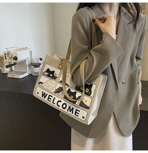 Detail of canvas tote bag featuring cute cartoon cat prints and khaki trim accent