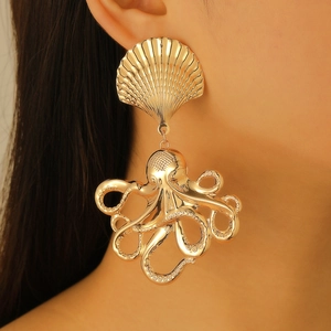 Close-up of golden oversized octopus earrings with shell detail on a female model