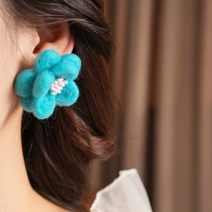 Vue détaillée d'une boucle d'oreille fleur bleue en peluche avec perles sur mannequin